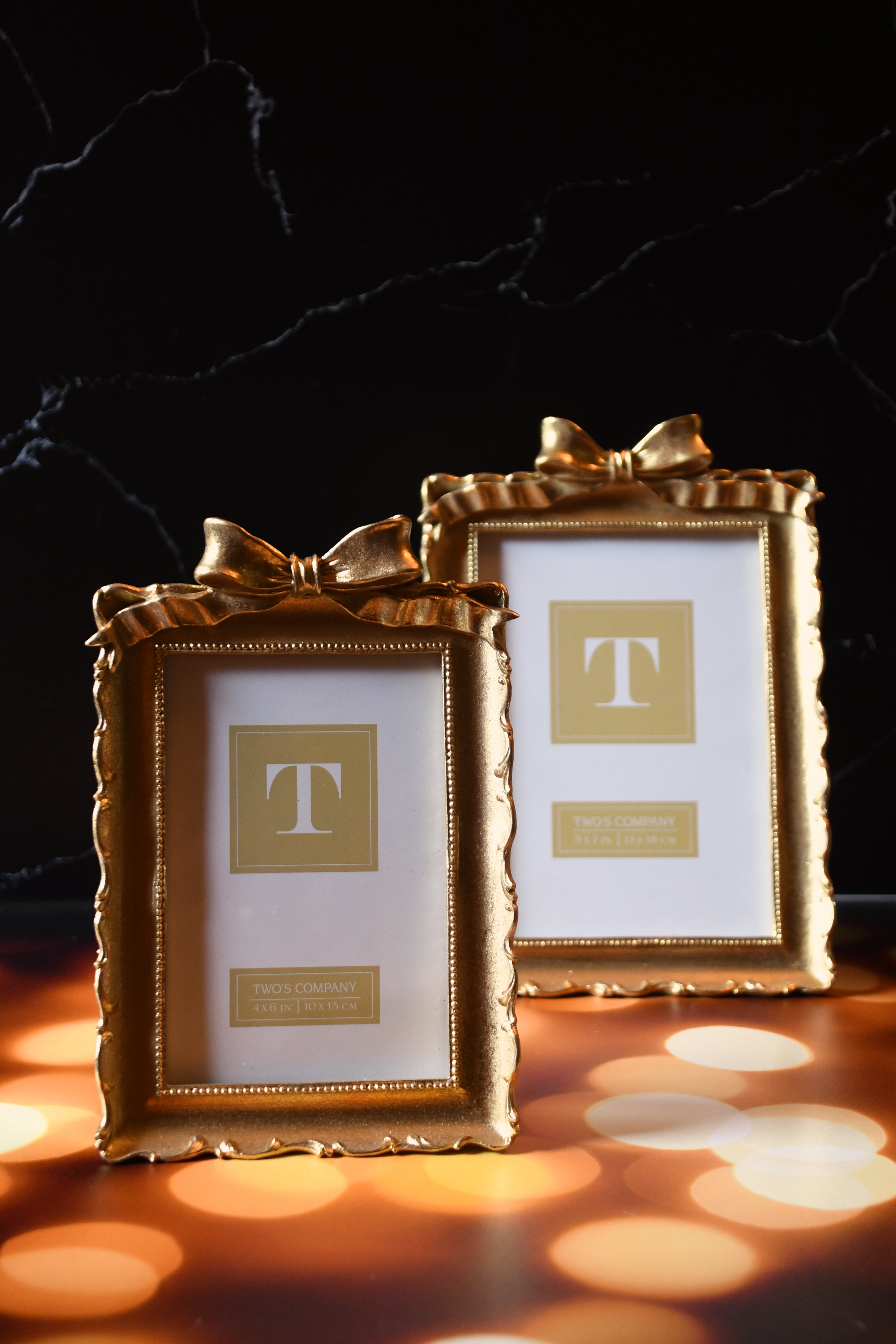 Two gold picture frames with a bow on a dark background