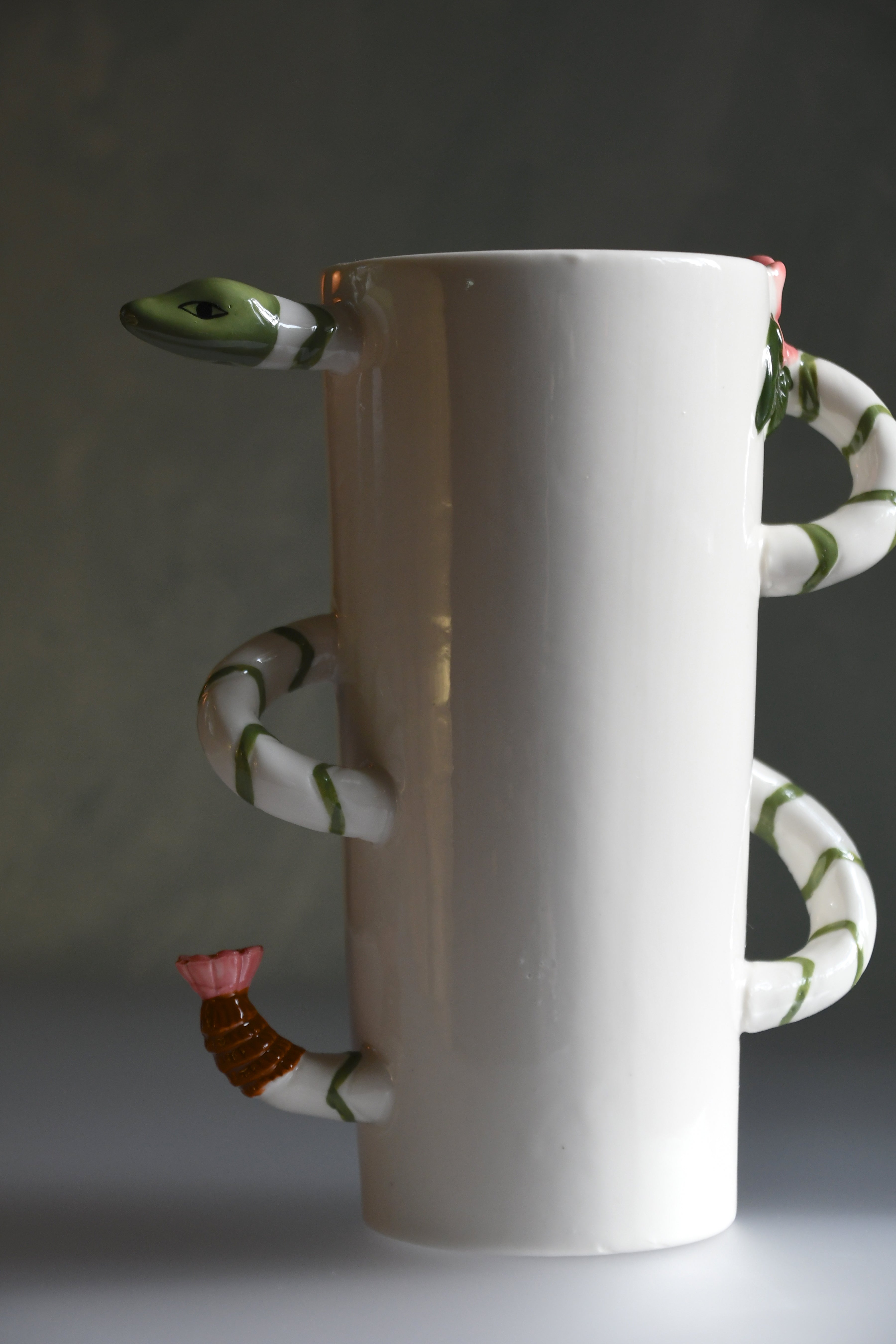 White ceramic vase with snake-like handles on a dark background
