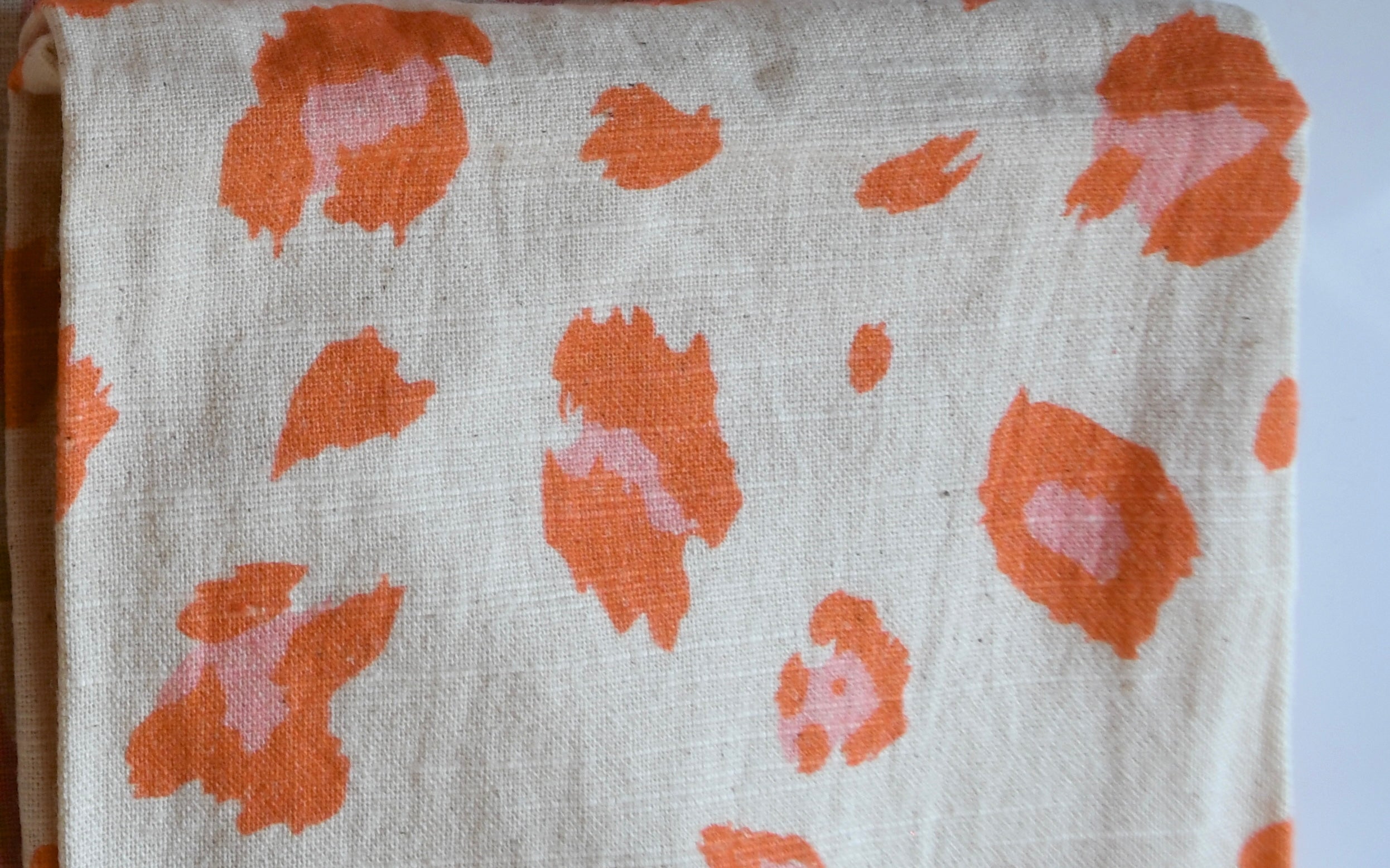 Fabric with orange floral patterns on a white background