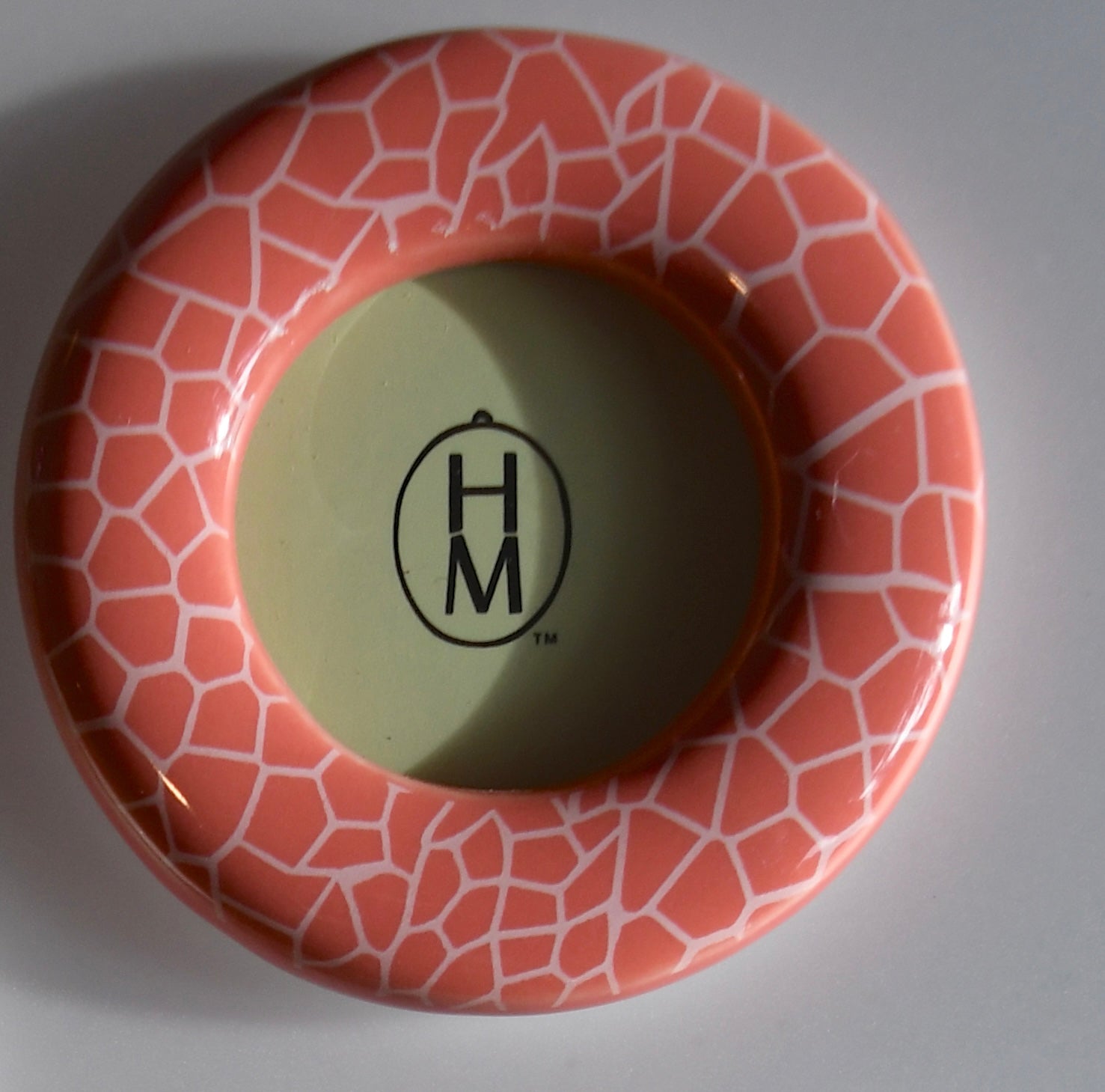 Ceramic frame with geometric pattern and 'HM' logo on a gray background