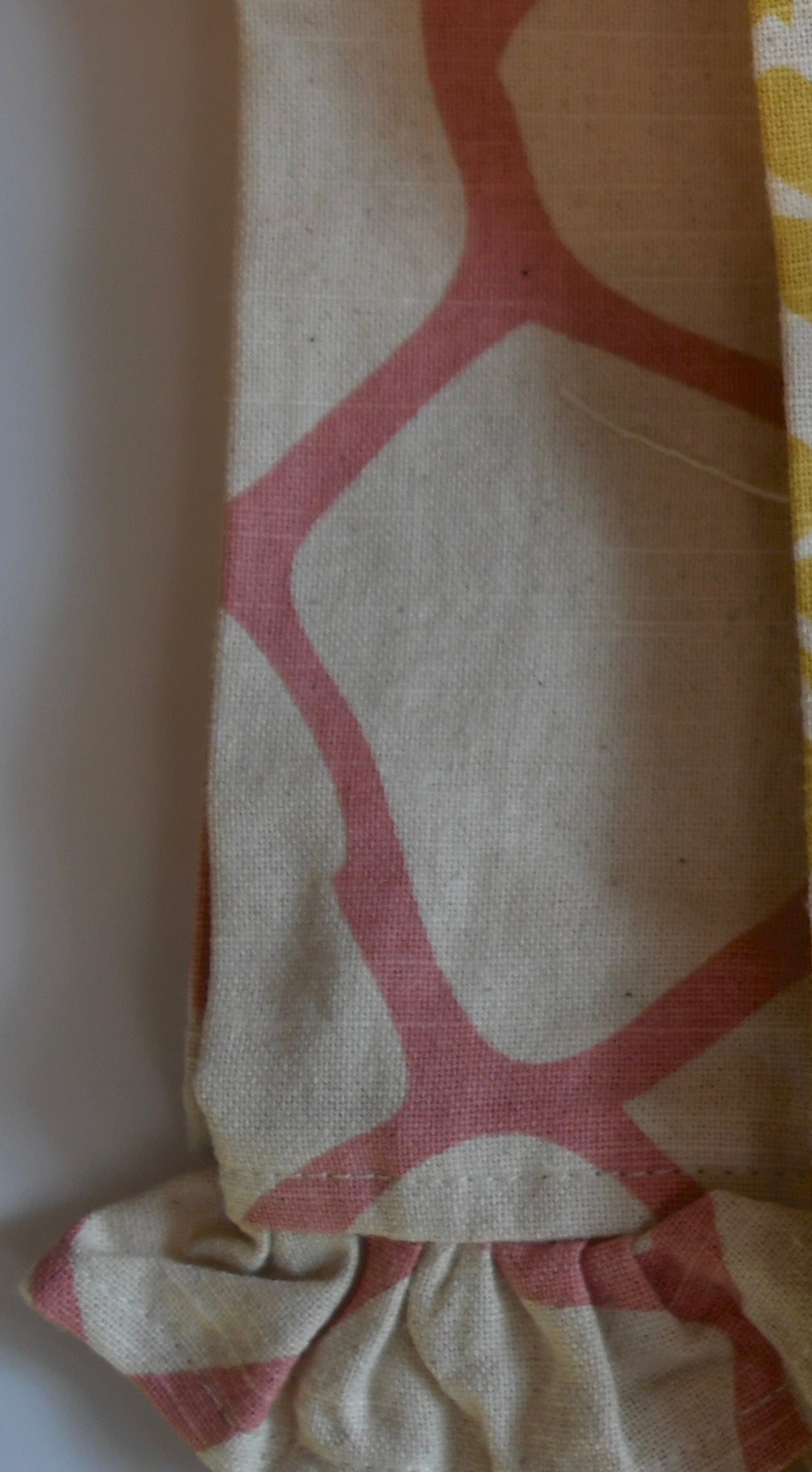 Close-up of beige fabric with pink geometric pattern on a white background