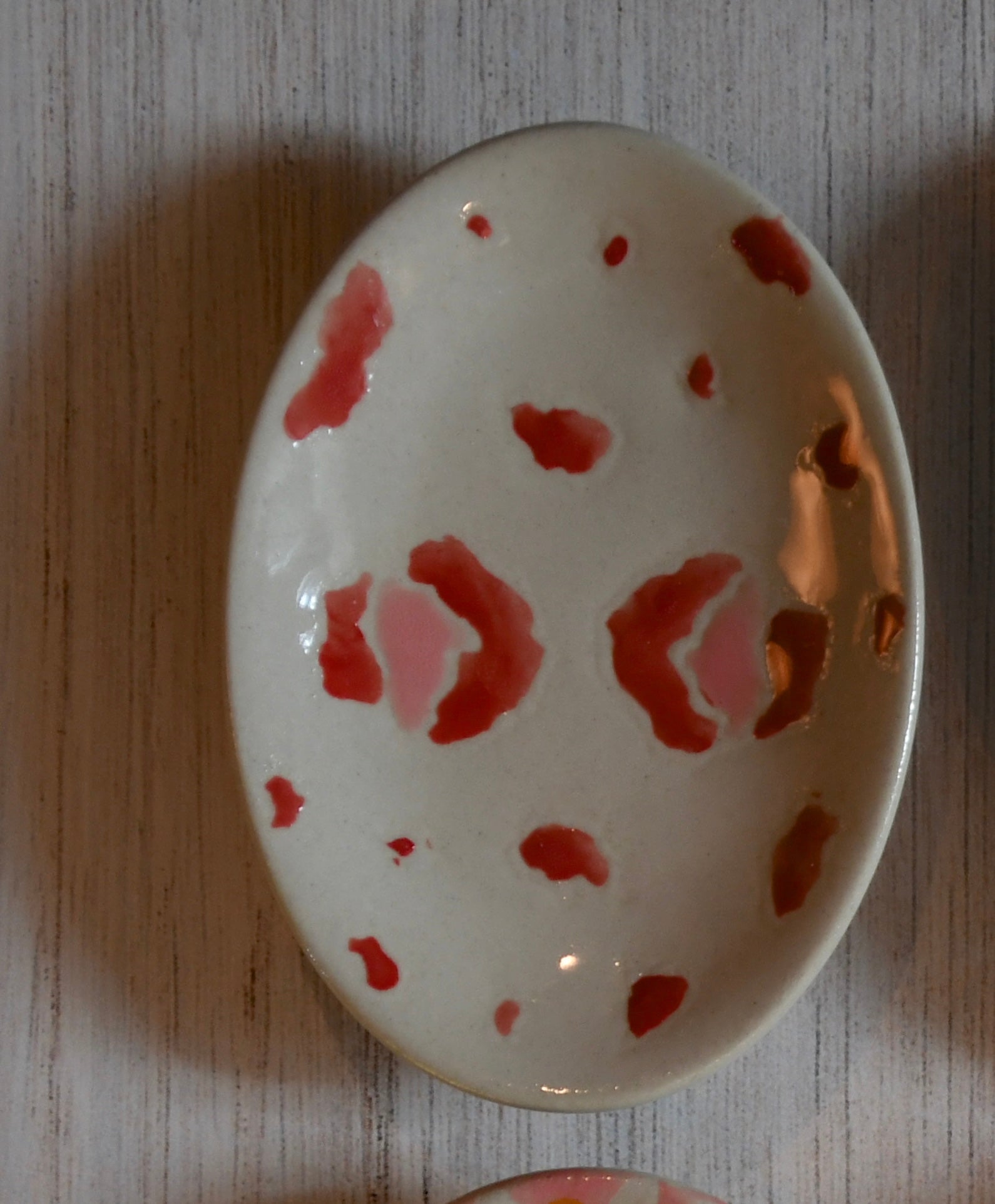 Small ceramic dish with red floral patterns on a wooden surface