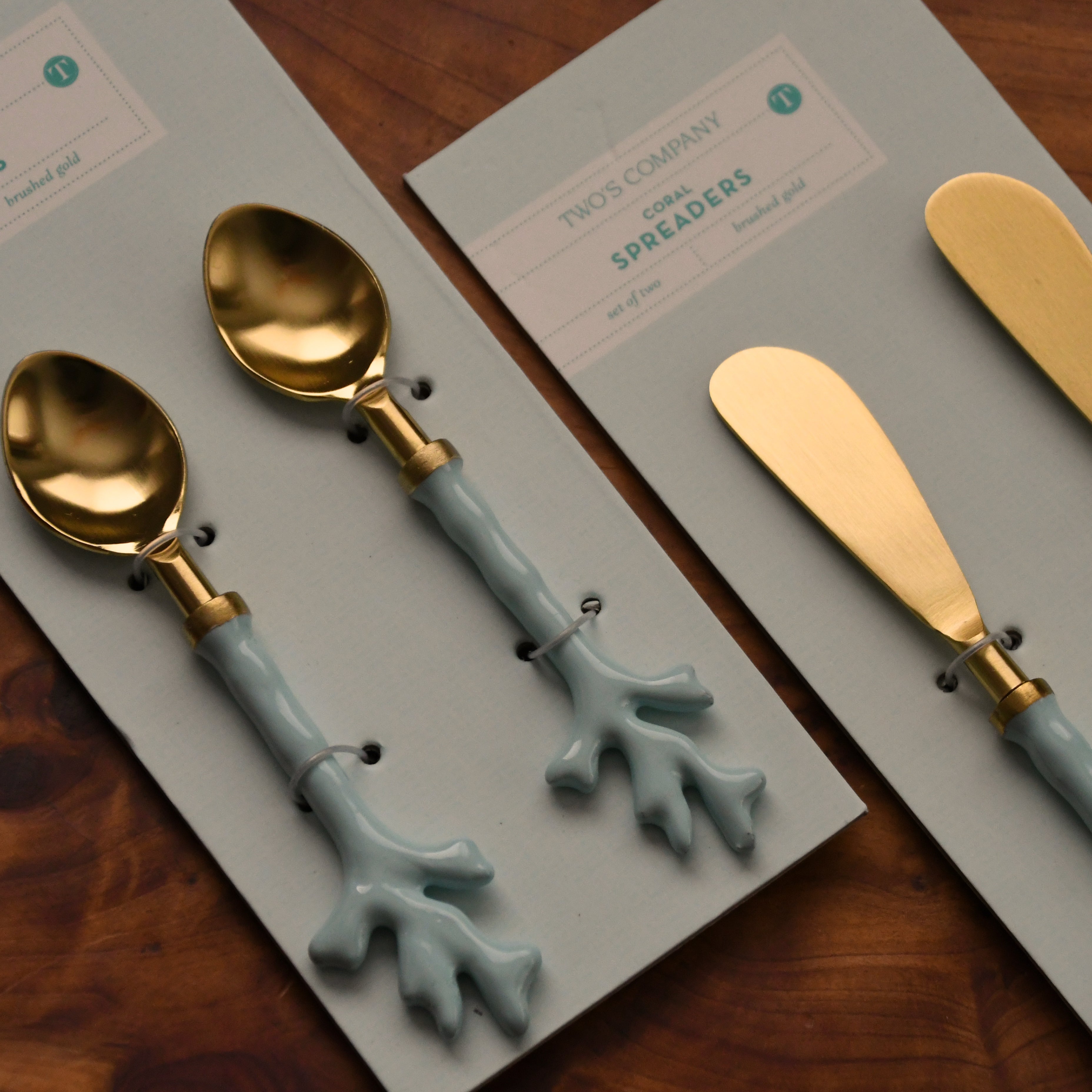 Set of gold and blue spoons and spreaders on branded cards on a wooden surface