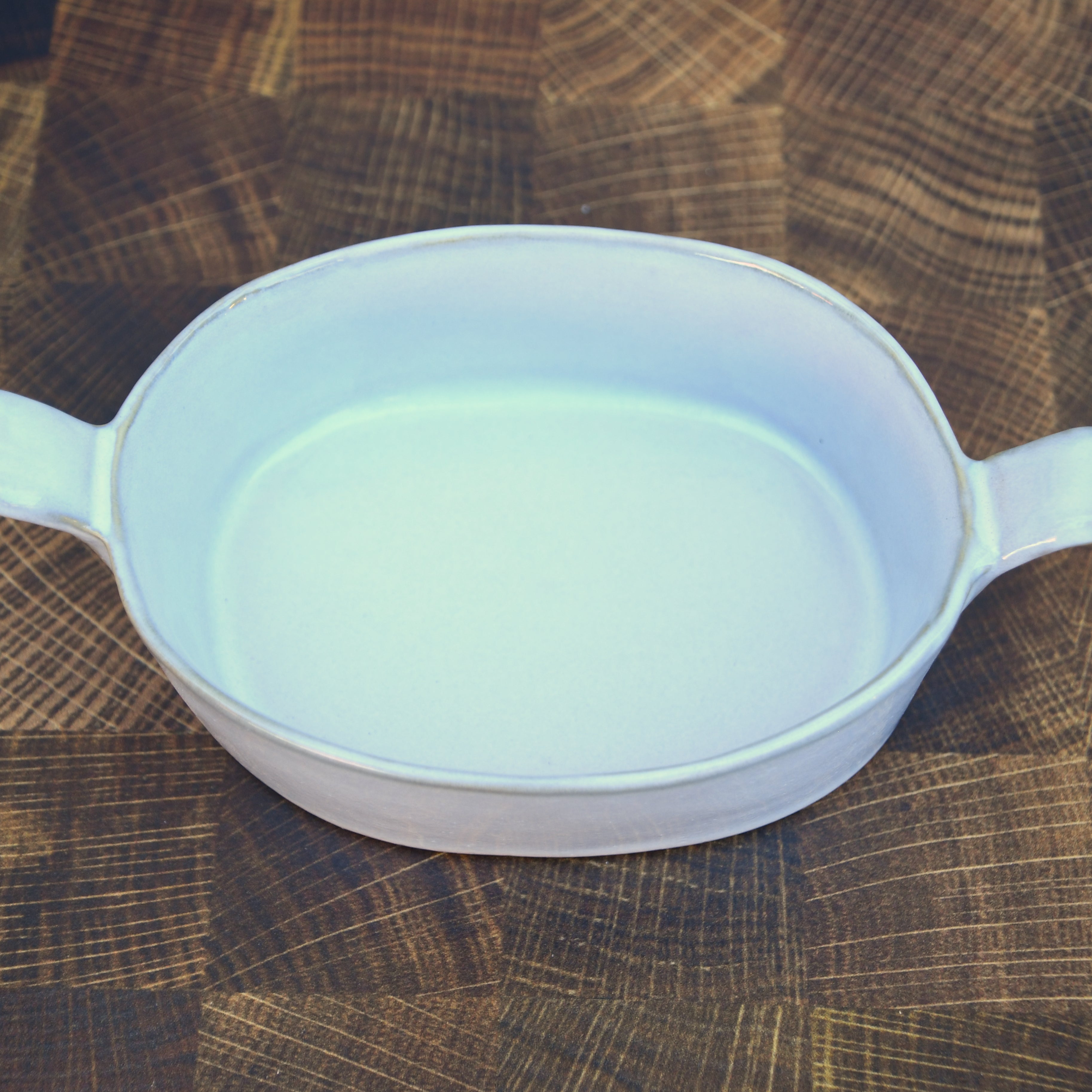 Stoneware baker with handles. White glaze. Dishwasher, oven and microwave safe.