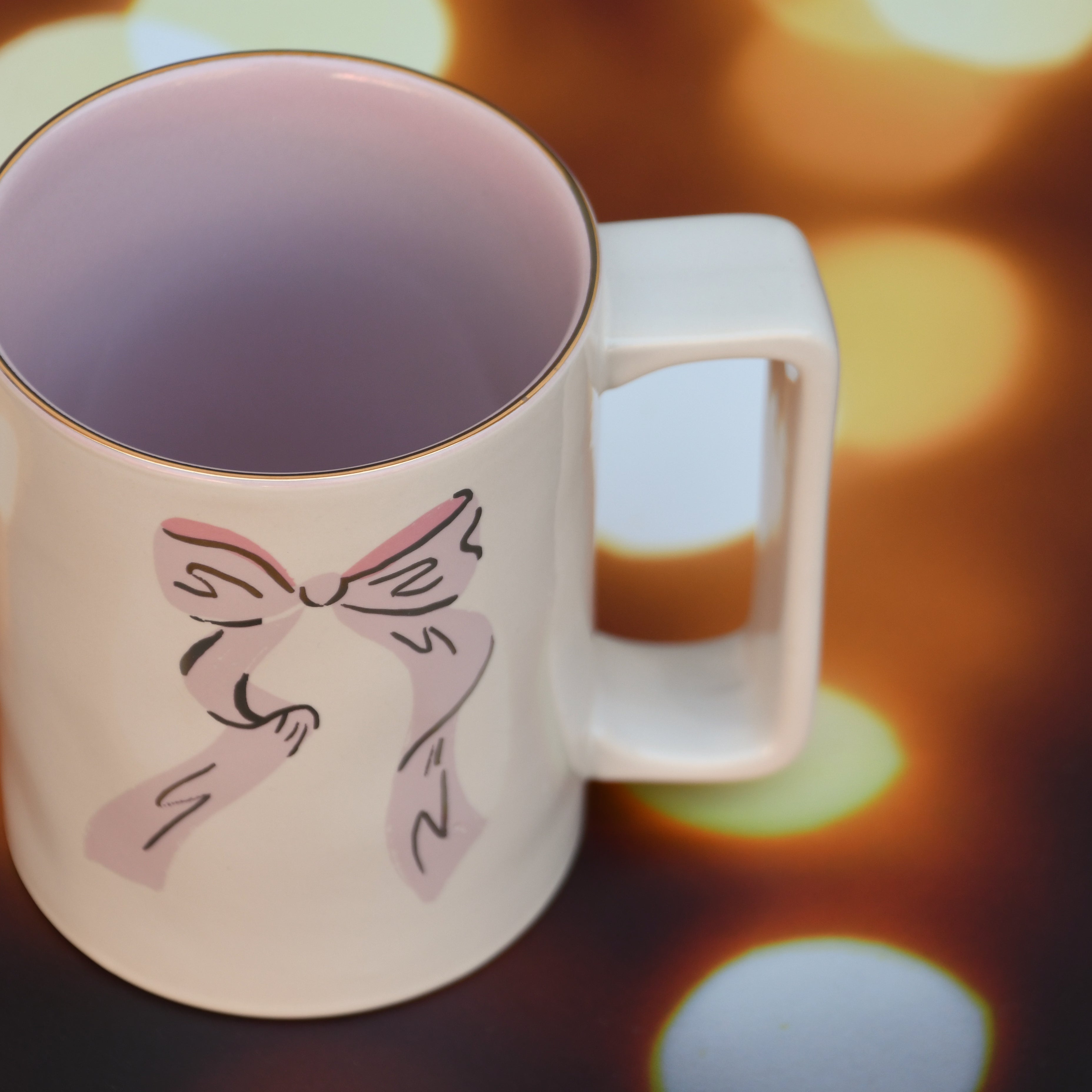 Ceramic mug with pink bow and gold detail.
