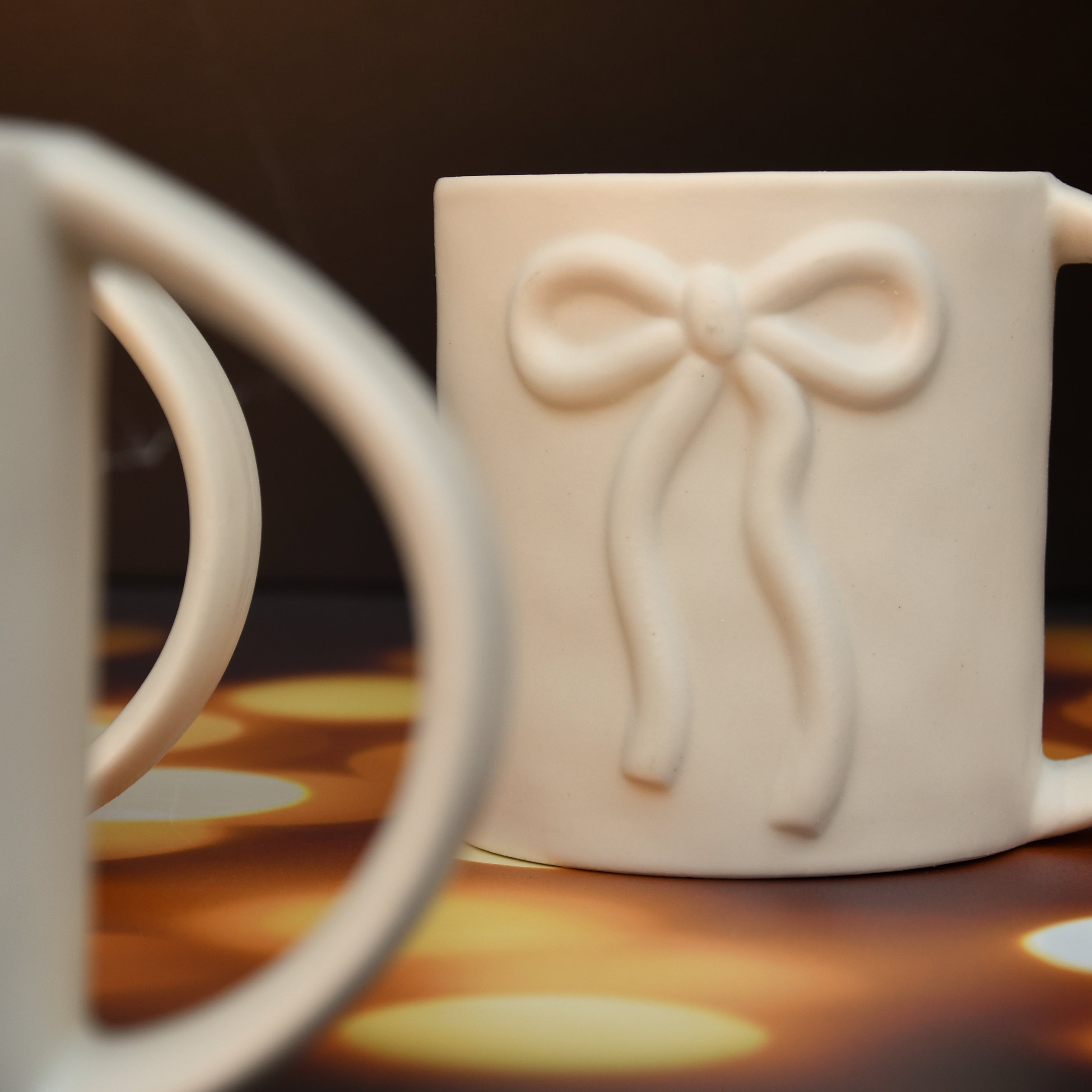 White ceramic mug with raised bow design. 16oz.
