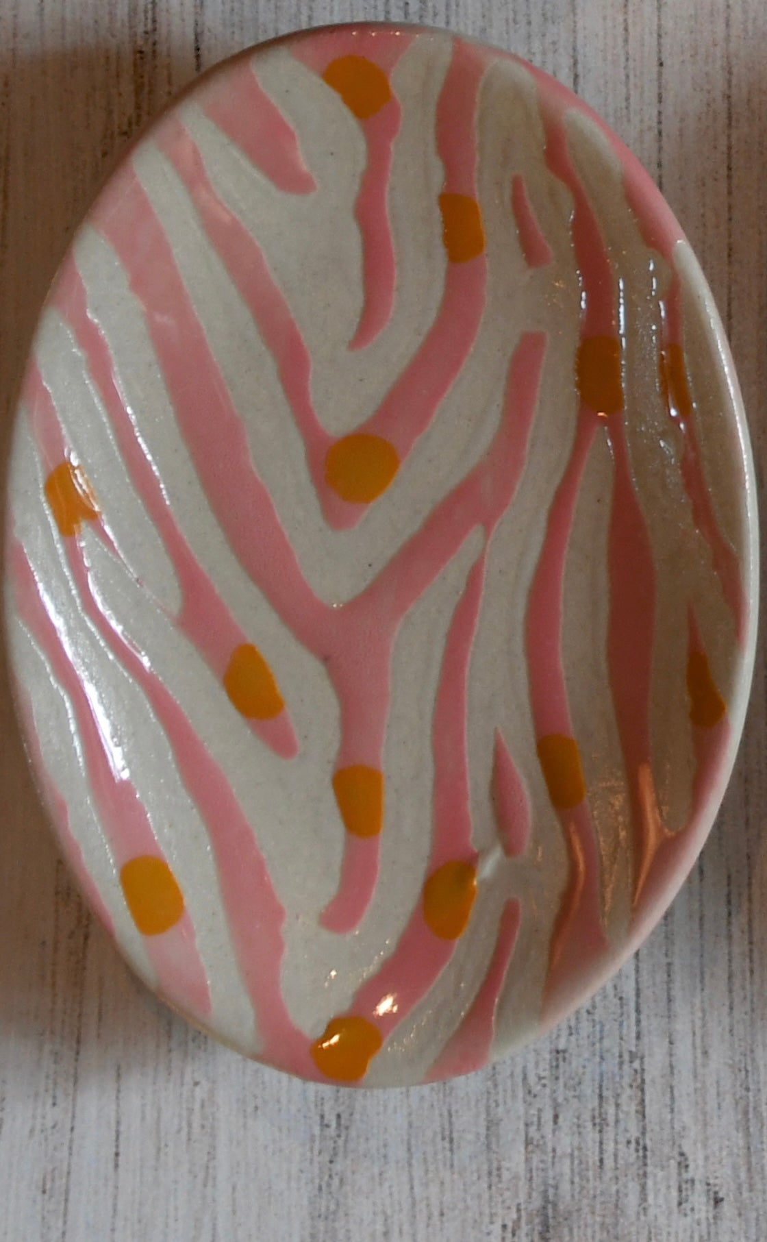Round ceramic plate with pink and white abstract design on a wooden surface