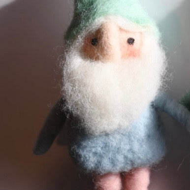 Felted gnome figurine with green hat and gray outfit on a neutral background