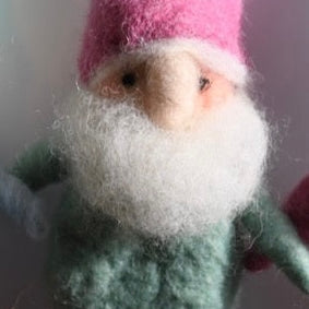 Small gnome figurine with a pink hat on a plain background