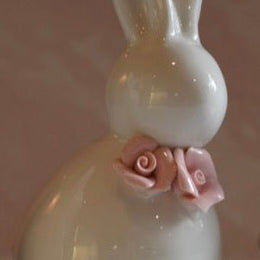 White ceramic bunny figurine with a pink bow on a light background