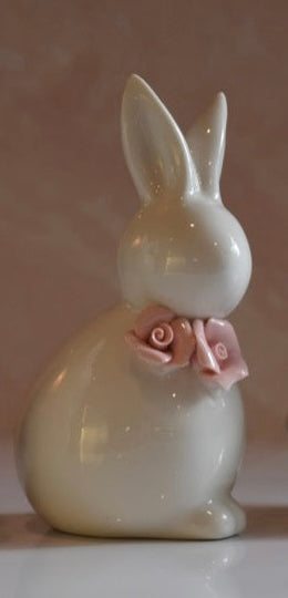 White ceramic bunny figurine with a pink bow on a light background