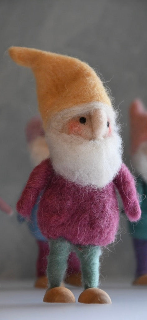 Felted gnome figurine with a yellow hat and pink outfit on a neutral background