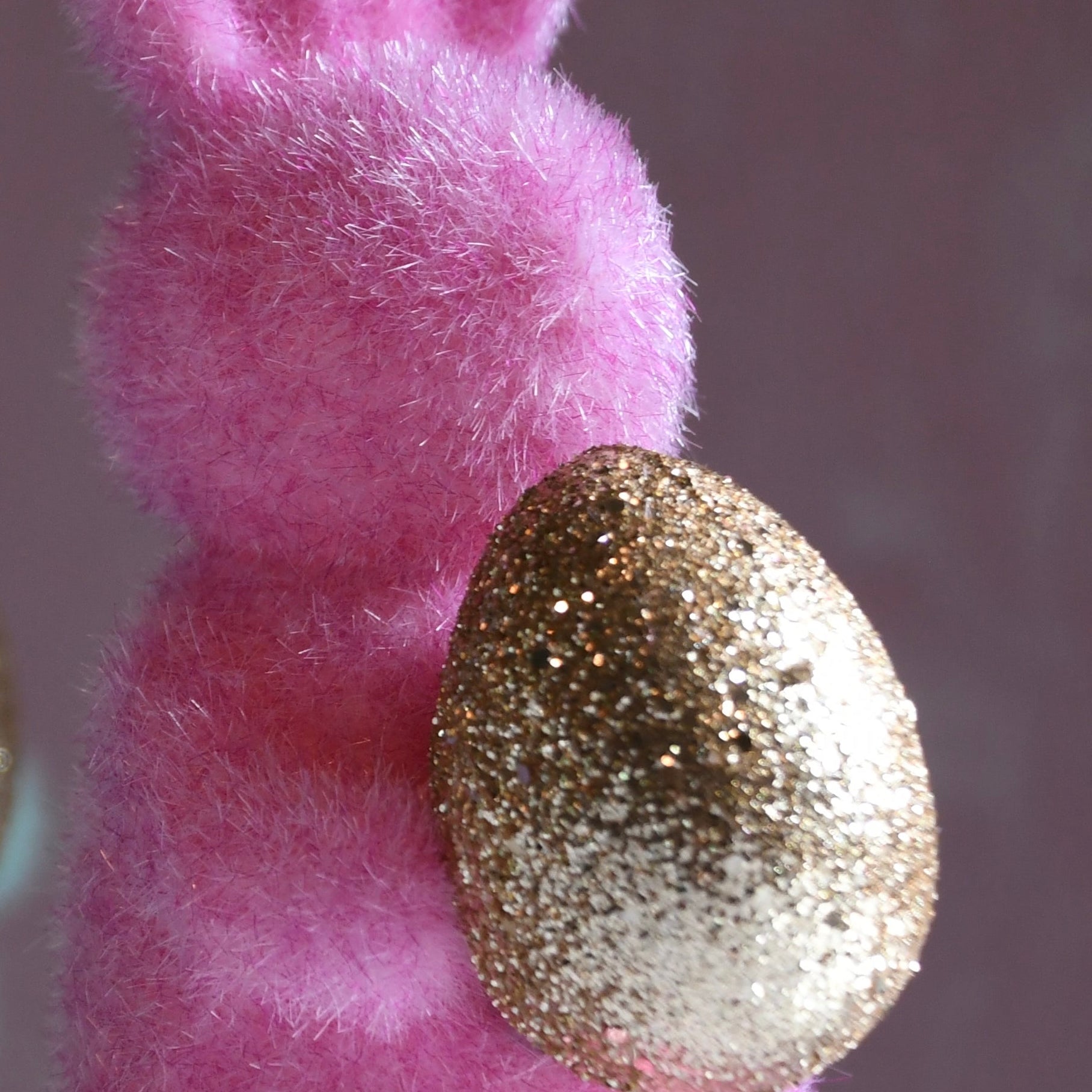 Pink fluffy bunny with a gold glittery egg on a neutral background