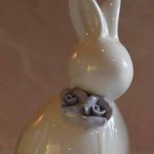 White ceramic rabbit figurine with gray flowers on a beige background