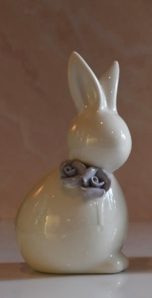 White ceramic rabbit figurine with gray flowers on a beige background