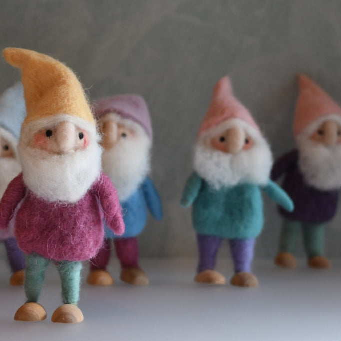 Five colorful gnome figurines with different colored hats and outfits on a neutral background