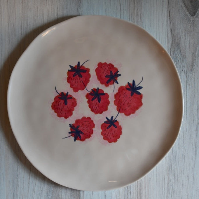 Beige plate with red floral patterns on a wooden surface