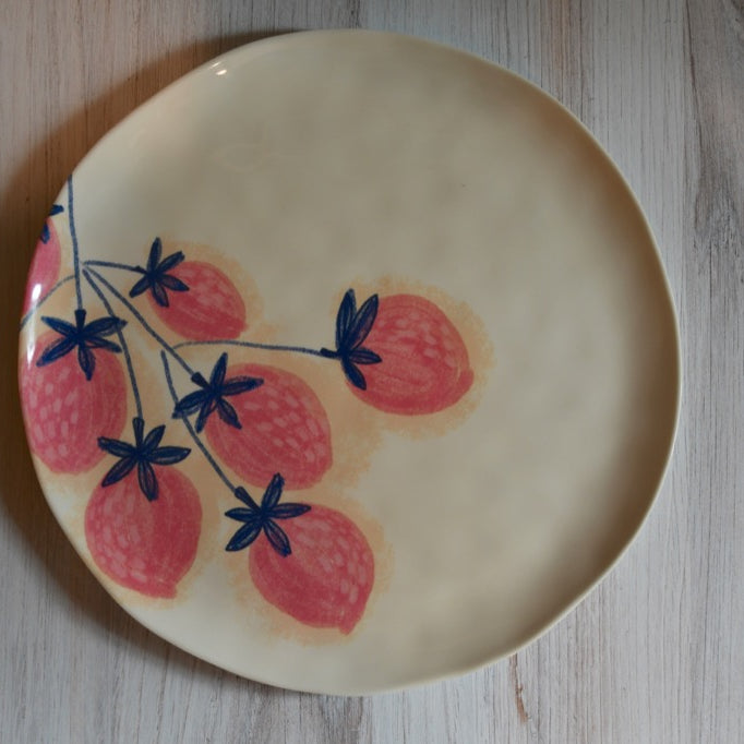 Ceramic plate with strawberry design on a wooden surface