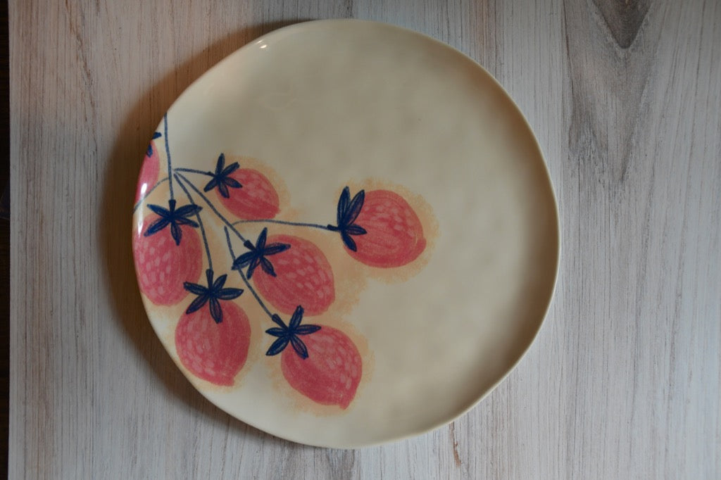 Ceramic plate with strawberry design on a wooden surface