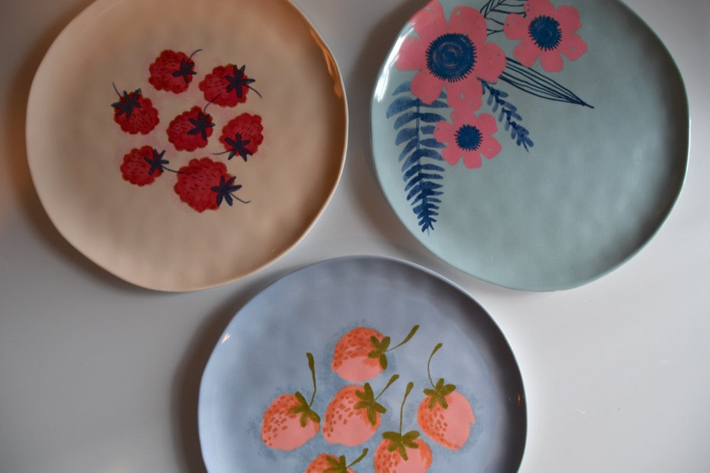 Three decorative plates with floral and strawberry designs on a white surface