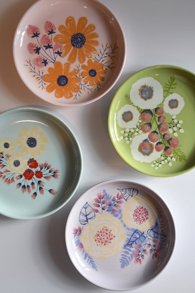 Four decorative plates with floral designs on a light gray background