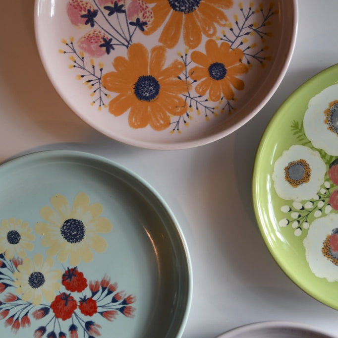 Set of colorful ceramic plates with floral designs on a white surface