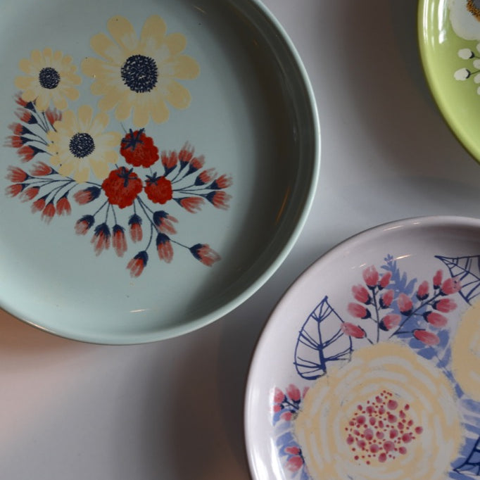 Set of decorative plates with floral patterns on a light gray surface