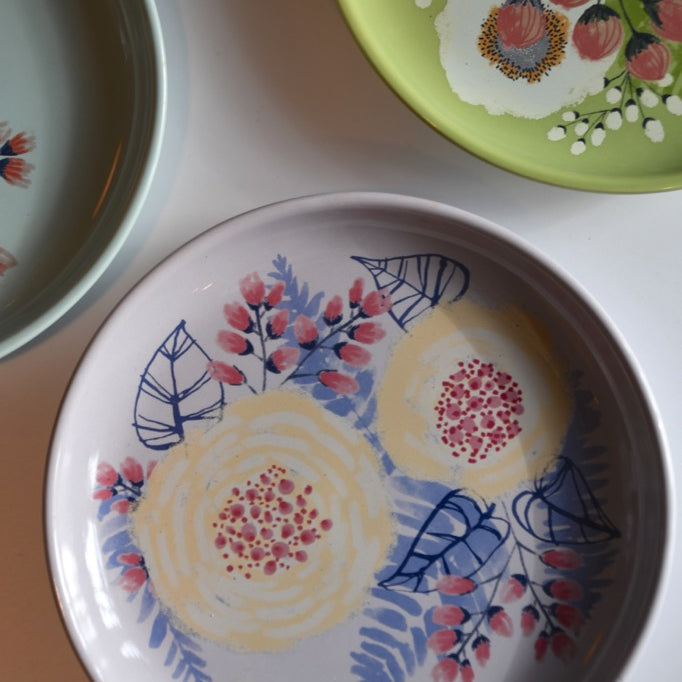 Three ceramic plates with floral designs on a light background