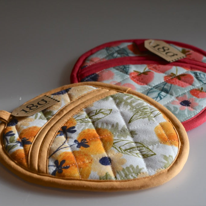 Set of fabric potholders with floral and strawberry patterns on a gray background