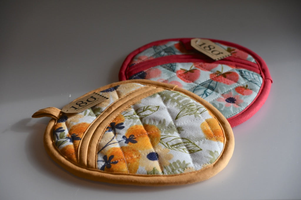 Set of fabric potholders with floral and strawberry patterns on a gray background