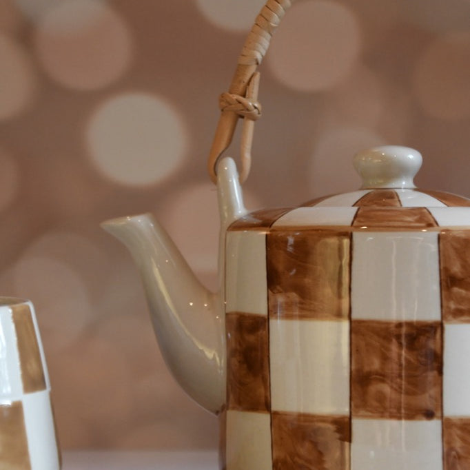 Checkered ceramic teapot on a blurred background