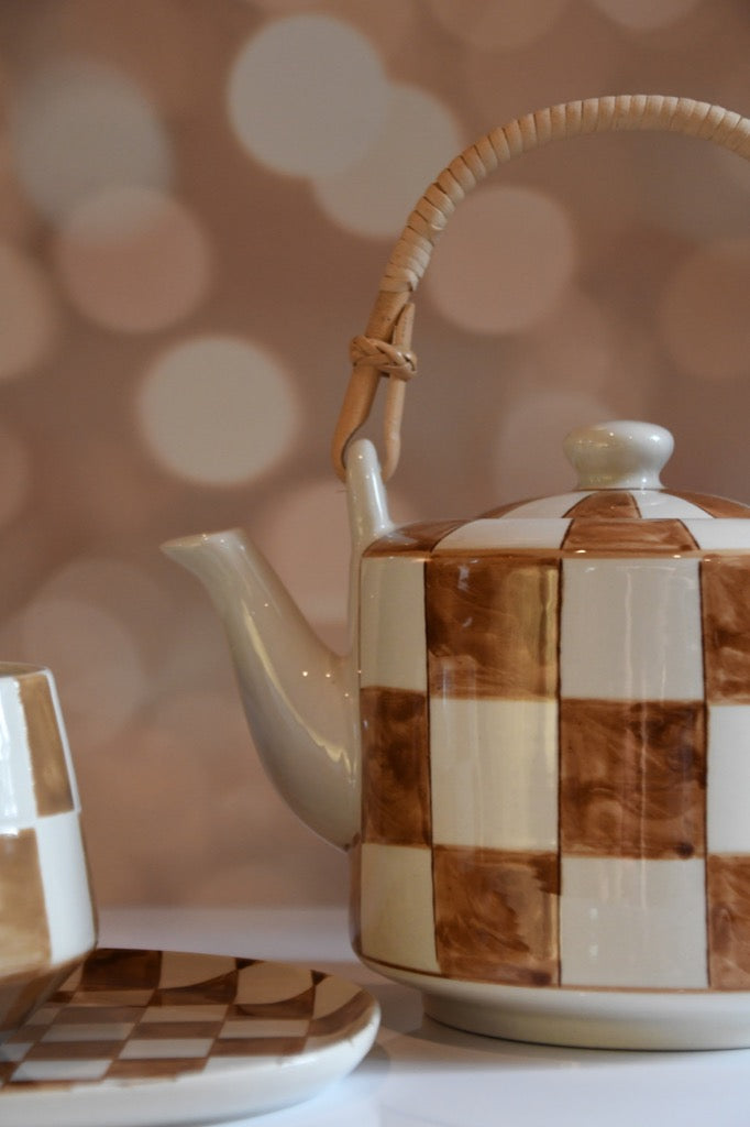 Checkered ceramic teapot on a blurred background