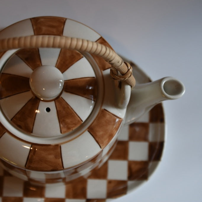 Teapot with brown and white checkered pattern on a plain background
