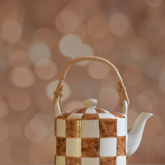 Checkered teapot with a wooden handle on a blurred background