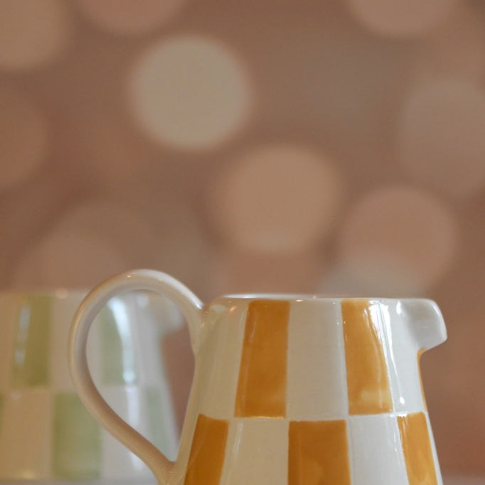 Checkered ceramic pitcher on a blurred background