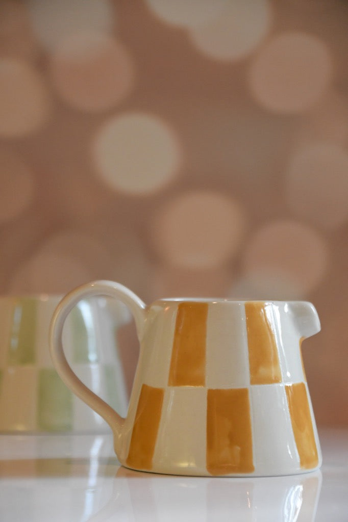 Checkered ceramic pitcher on a blurred background