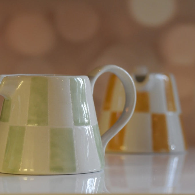 Green and white striped ceramic pitcher on a blurred background