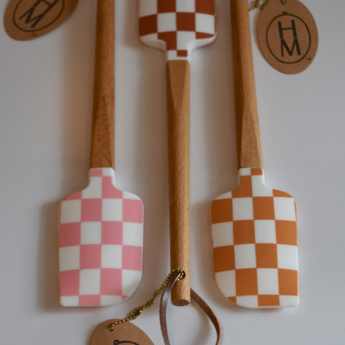 Set of three wooden spatulas with checkered patterns and 'HM' branding on a white background