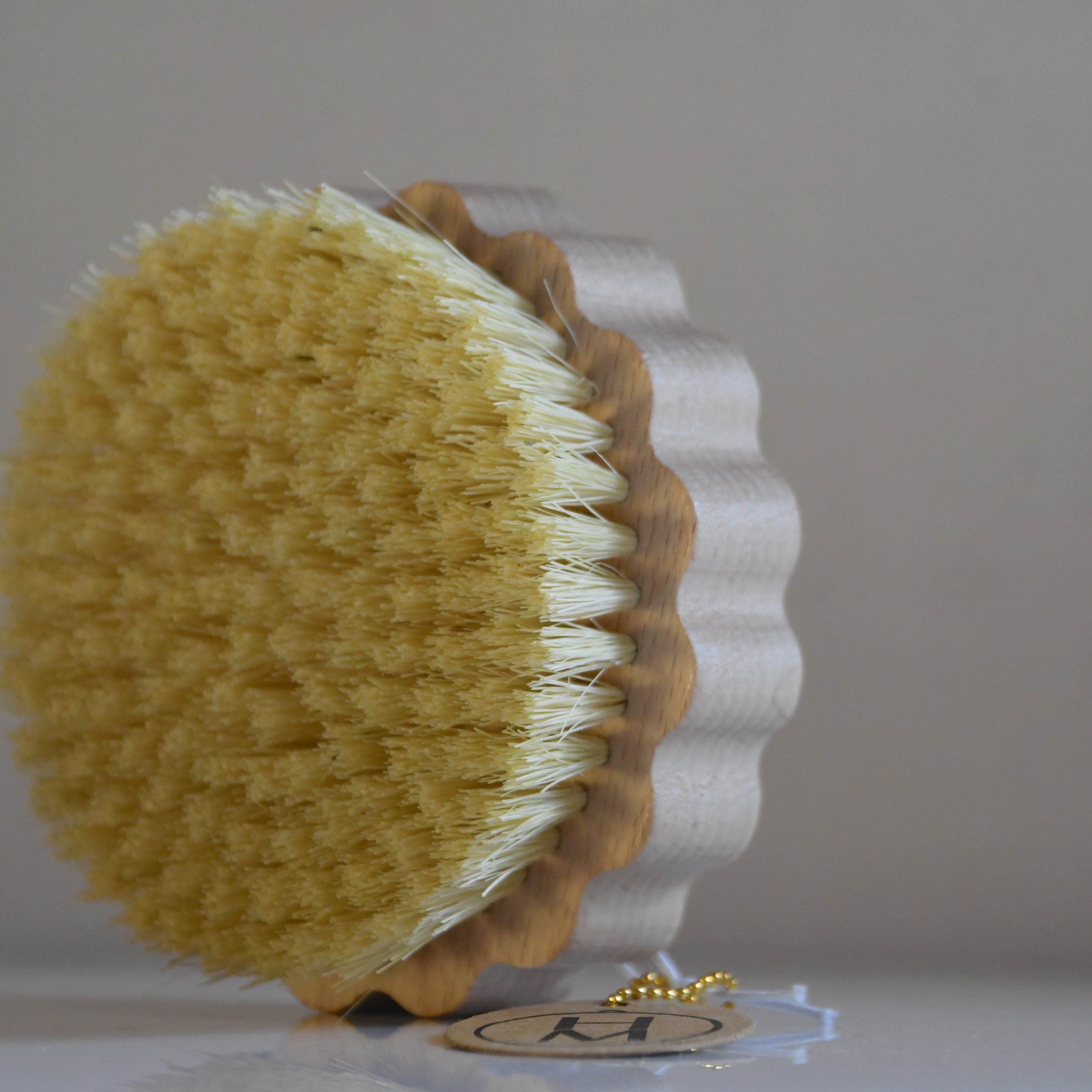 Round brush with yellow bristle head and brown handle on a white background