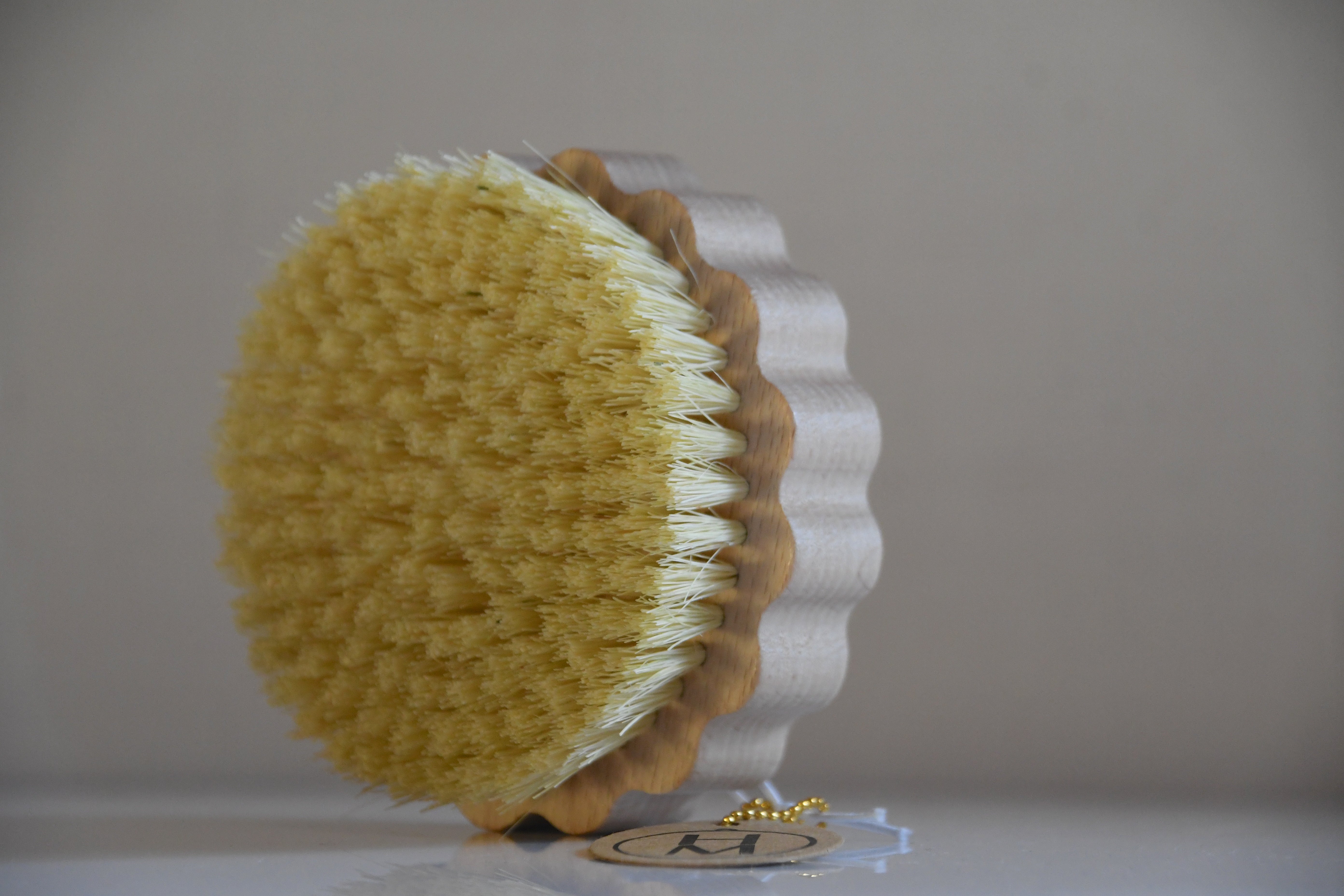 Round brush with yellow bristle head and brown handle on a white background