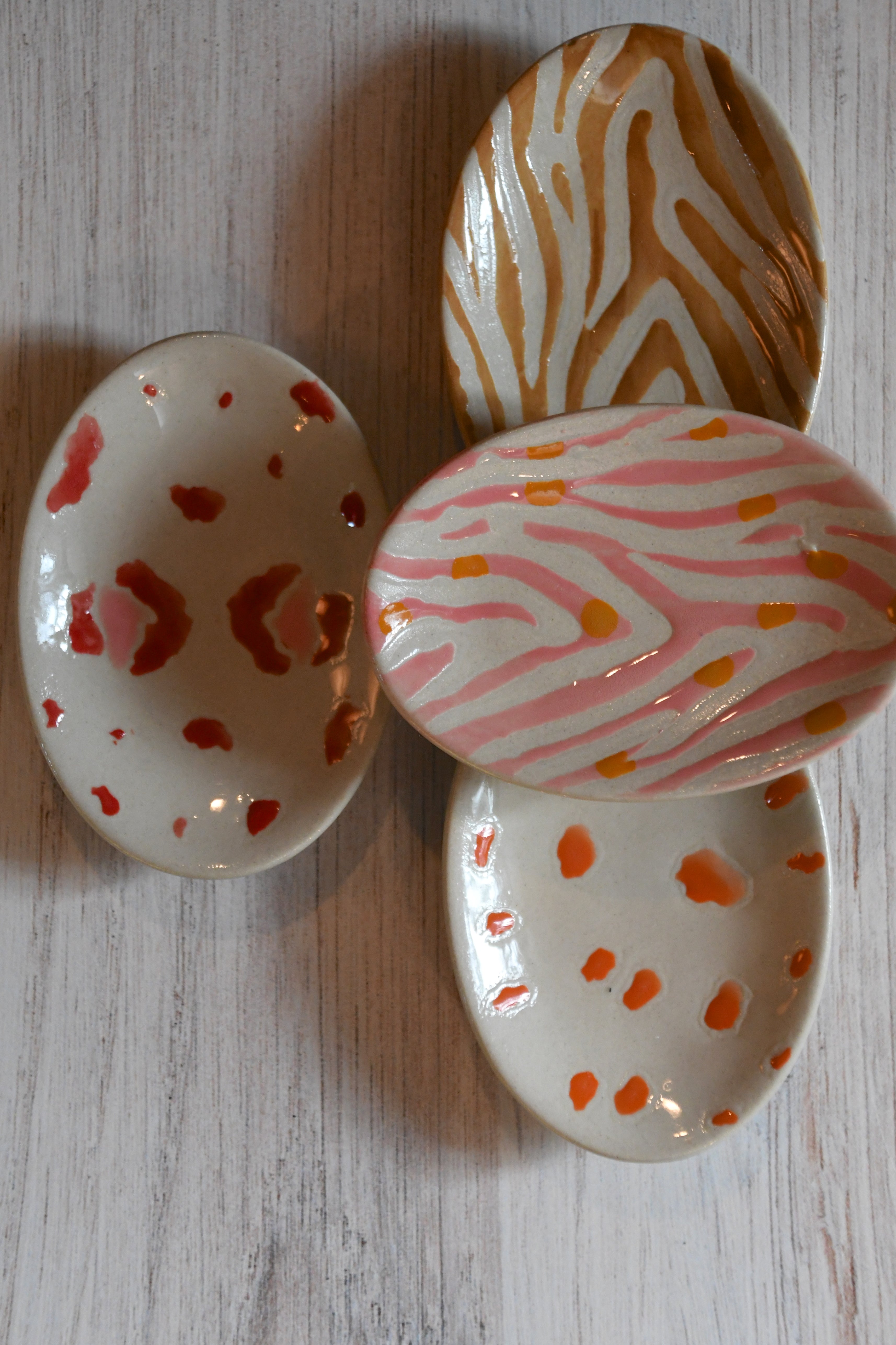 Three decorative ceramic plates with zebra and polka dot patterns on a wooden surface.
