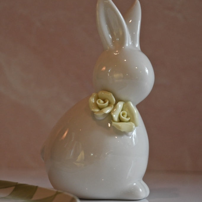 White ceramic bunny with a yellow rose on a pink background
