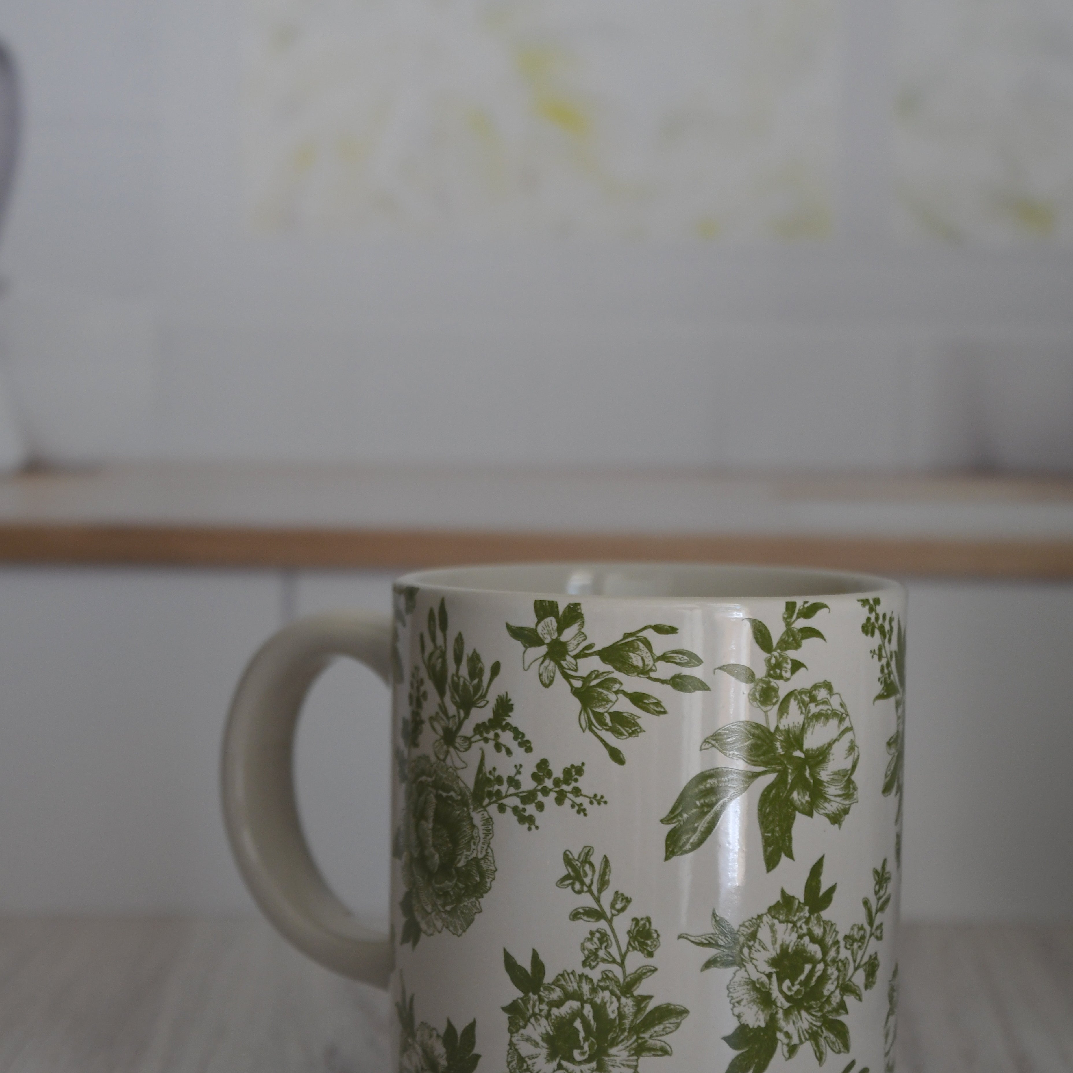 Mug with green floral pattern on a wooden surface