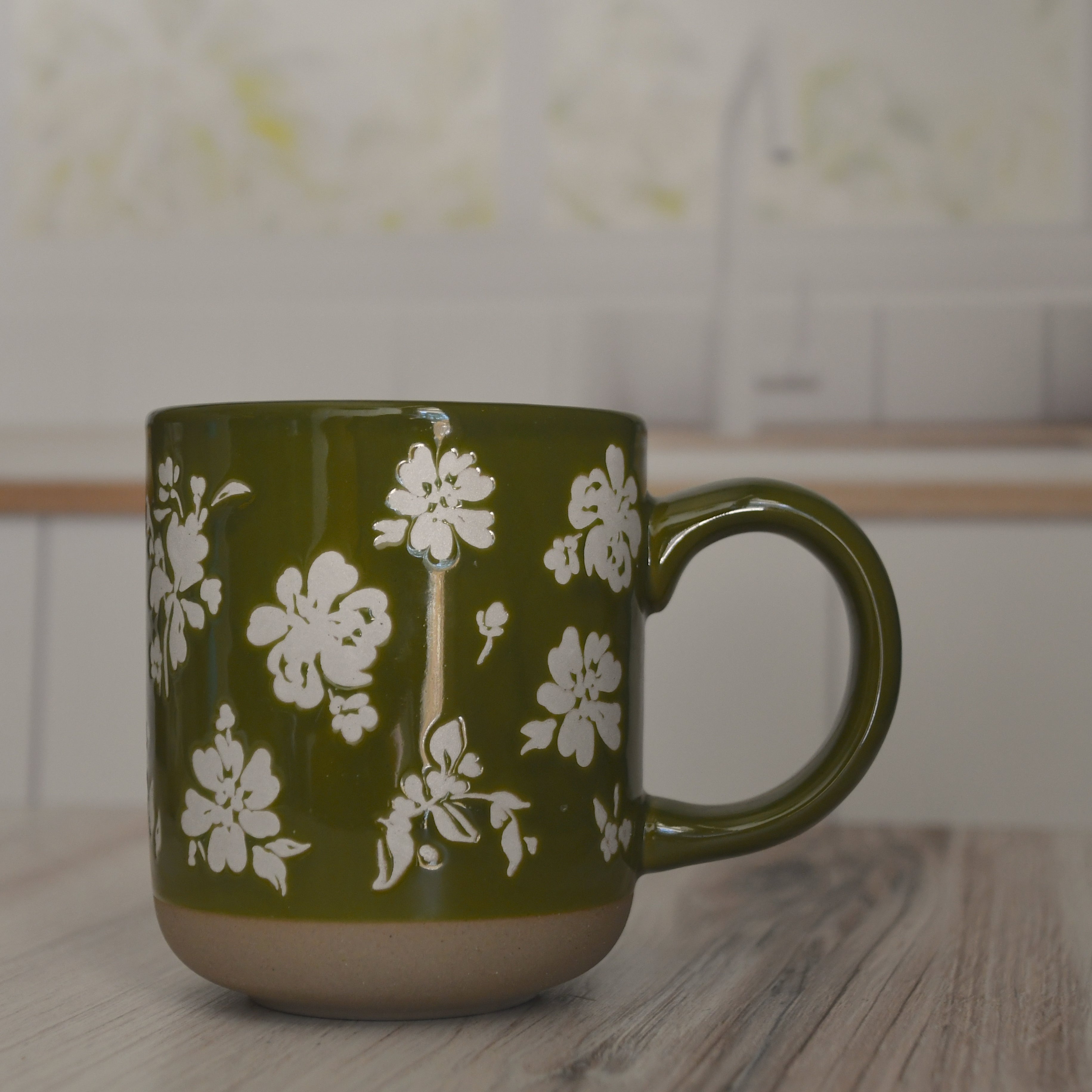 Green mug with white floral pattern on a kitchen counter