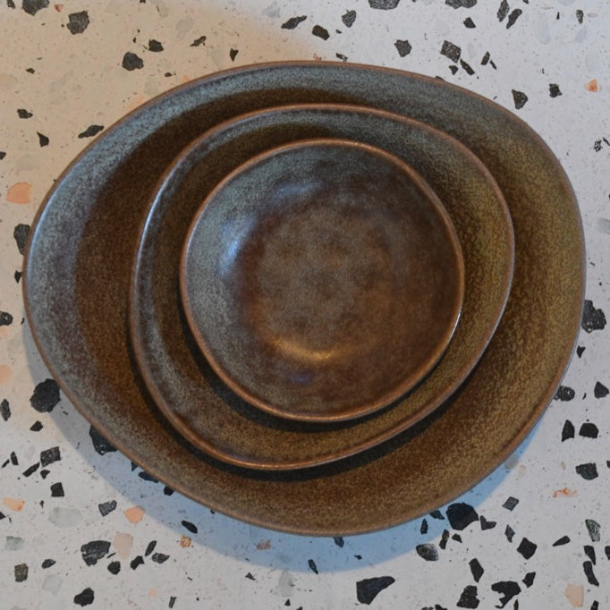 Stack of brown ceramic plates on a speckled surface