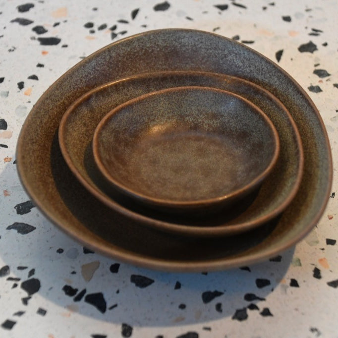 Set of three ceramic bowls stacked on a speckled surface
