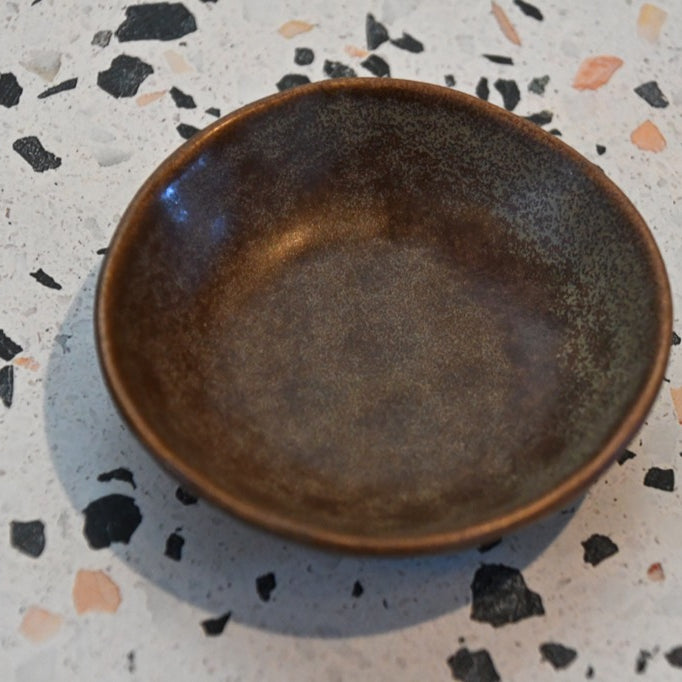Brown ceramic bowl on a speckled countertop