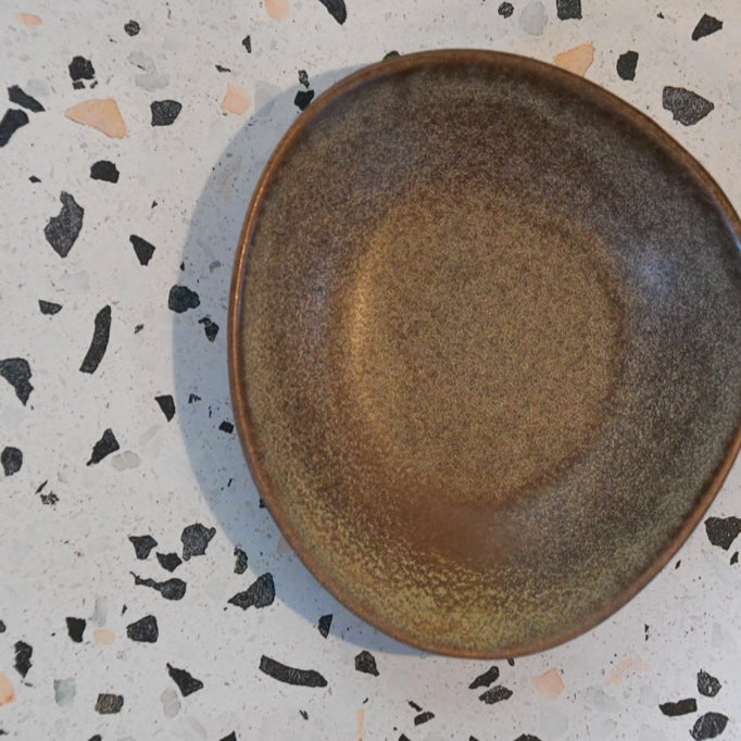 Brown ceramic plate on a speckled gray surface