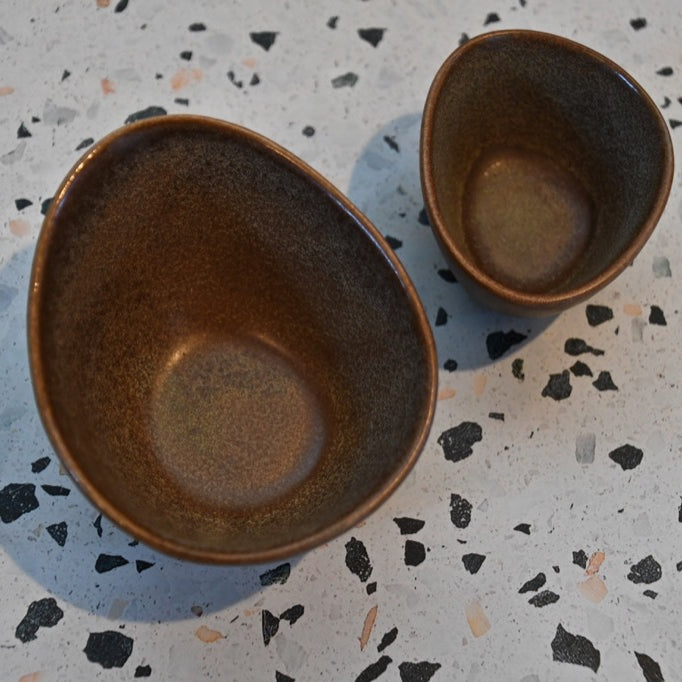 Two brown ceramic bowls on a speckled surface