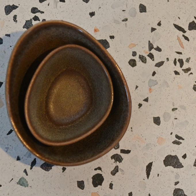 Three ceramic bowls stacked on a terrazzo countertop